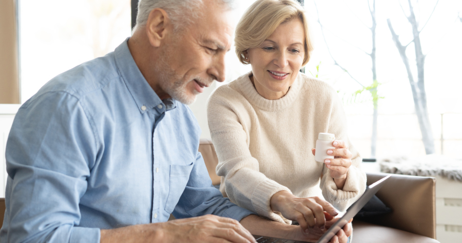 Senior couple with pills and laptop in living room